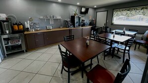 A restaurant with a counter, tables, chairs, and a television. - Royal Inn & Suites (Mountain Grove)