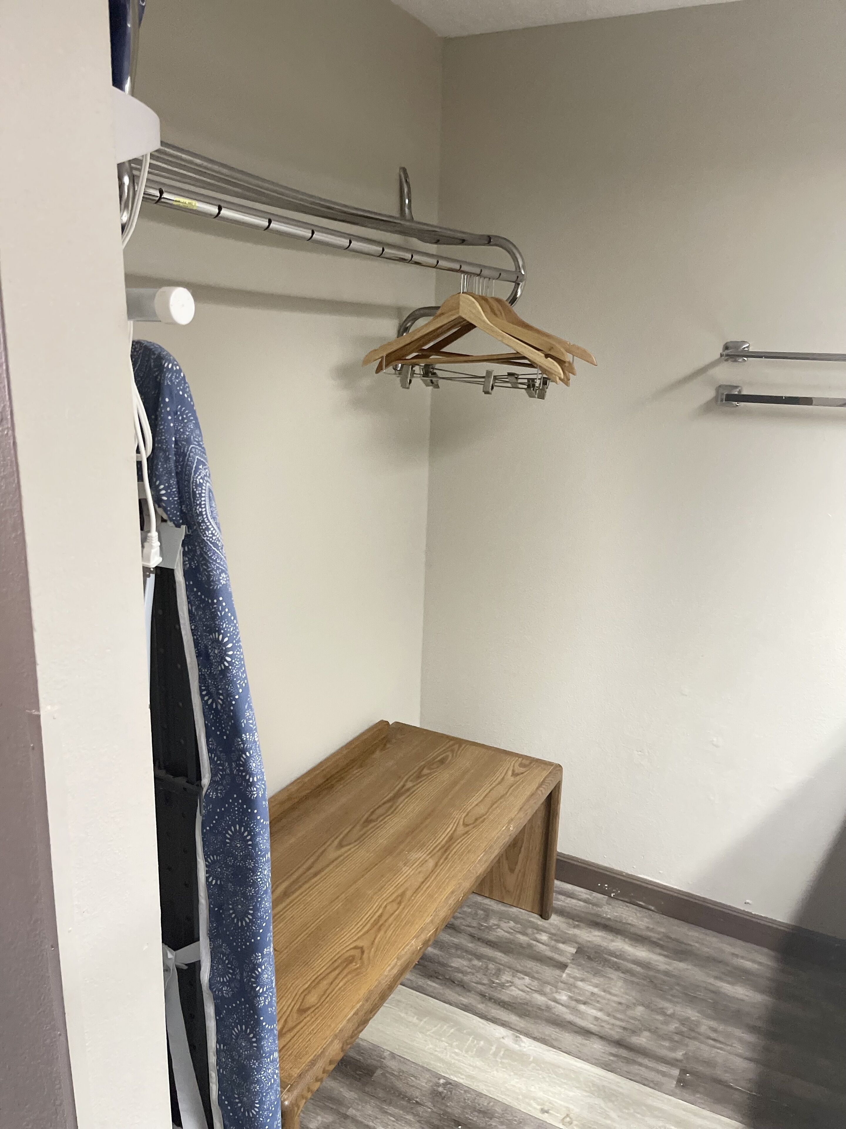 A small room with a wooden bench, a metal drying rack, and a towel hanging on a hook.