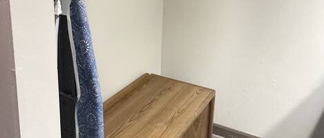 A small room with a wooden bench, a metal drying rack, and a towel hanging on a hook.
