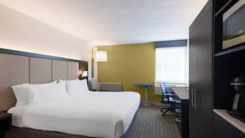 Habitación de hotel con una cama grande, un escritorio, una silla y un armario.