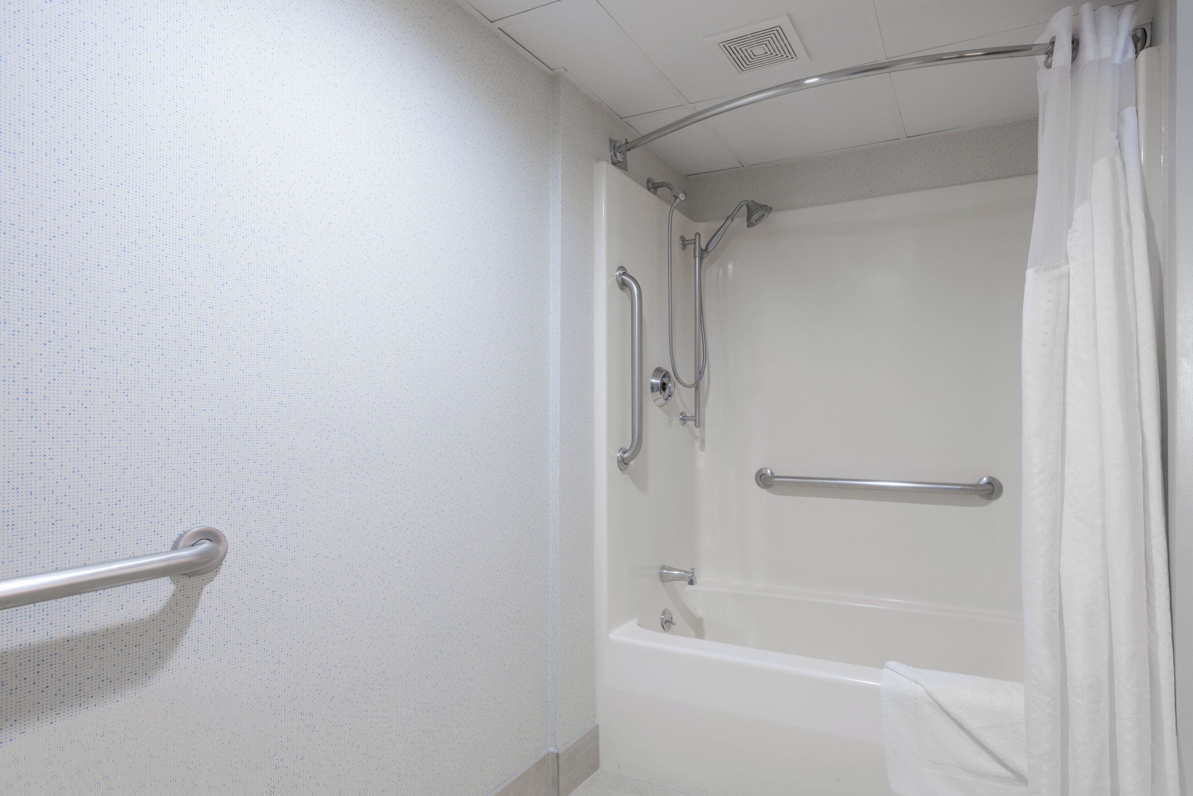 Un baño con bañera, ducha y barra de apoyo.