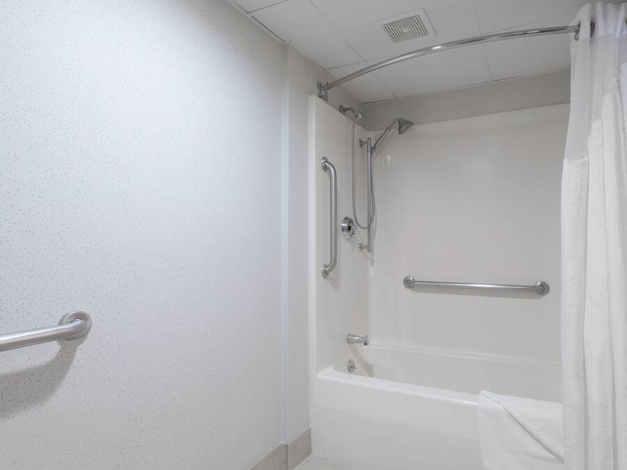 Un baño con bañera, ducha y barra de apoyo.