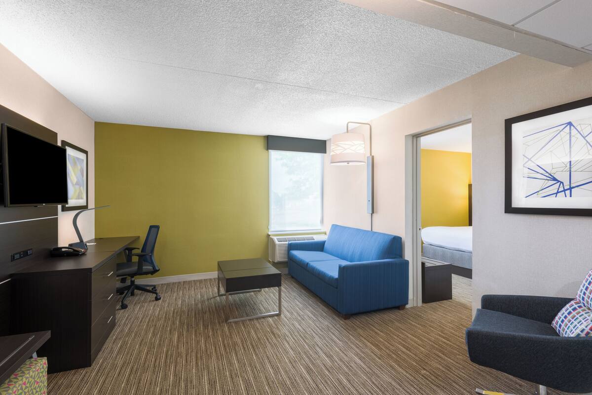 A hotel room with a desk, office chair, sofa, and a bed.