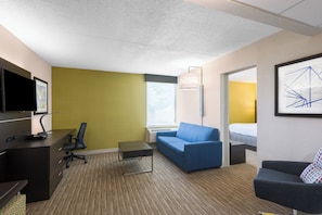 A hotel room with a desk, office chair, sofa, and a bed. - Holiday Inn Express Ramsey-Mahwah by IHG (Ramsey)