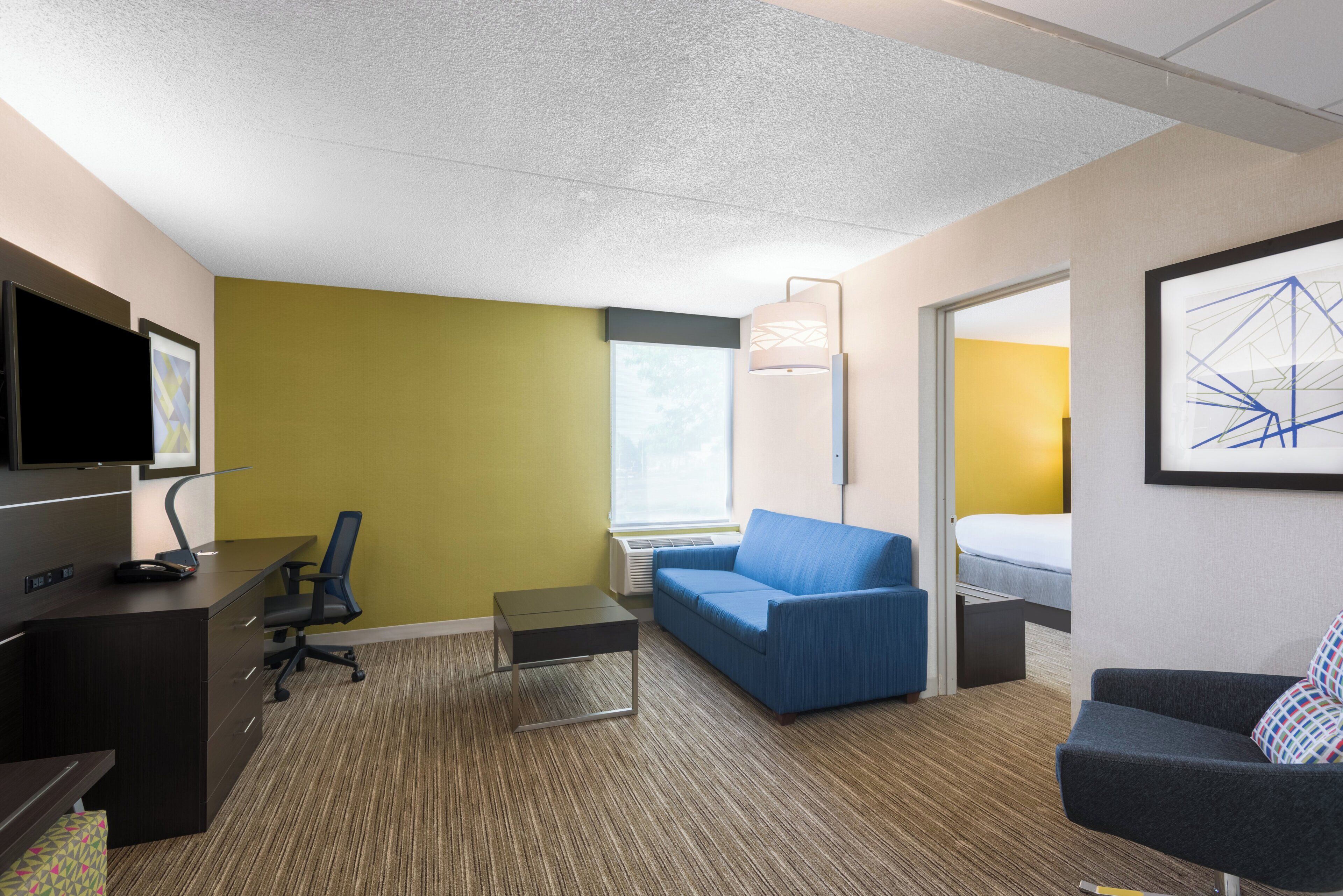 Une chambre d’hôtel équipée d’un bureau, d’un fauteuil de bureau, d’un canapé et d’un lit.
