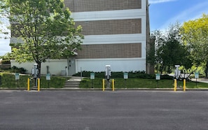 A building with multiple parking spaces, some marked for electric vehicles, and a tree in the foreground. - Holiday Inn Express Ramsey-Mahwah by IHG (Ramsey)