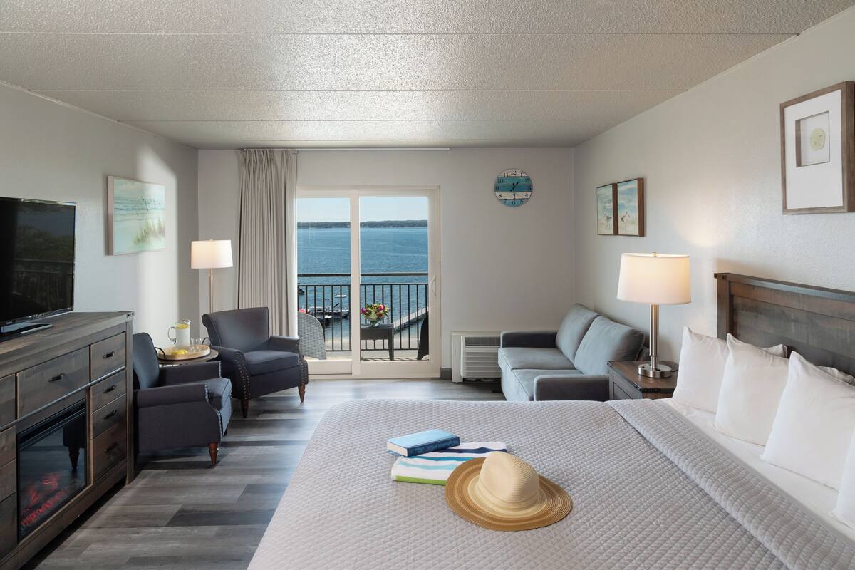 Une chambre d’hôtel avec un lit, une télévision, un bureau et une vue sur la mer.