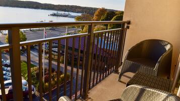 Un balcon avec des fauteuils en osier et une vue sur un lac et une jetée.