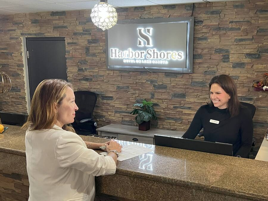 A reception desk at Harbor Shores Hotel with a stone wall backdrop and a sign above.