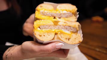 A person holding a sandwich with visible layers of meat and cheese.