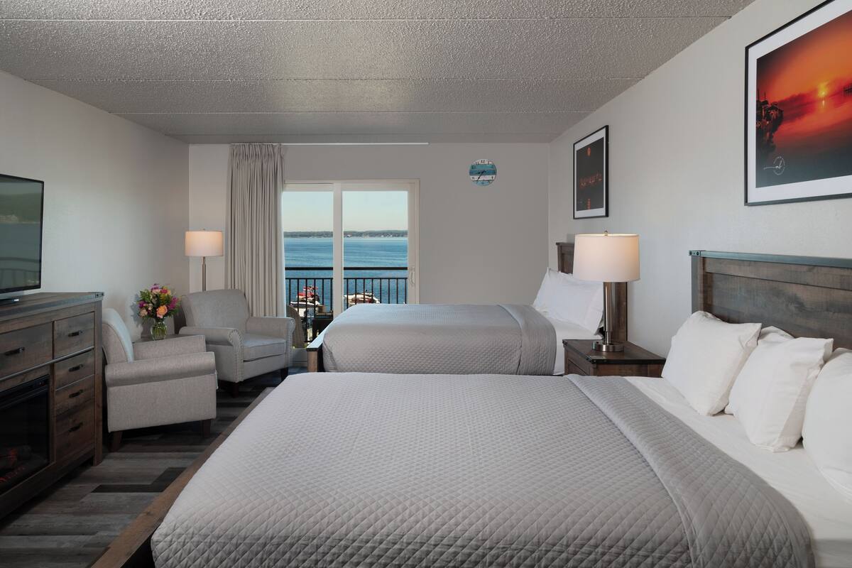 Une chambre d’hôtel avec deux lits, une télévision, un bureau et une vue sur la mer.