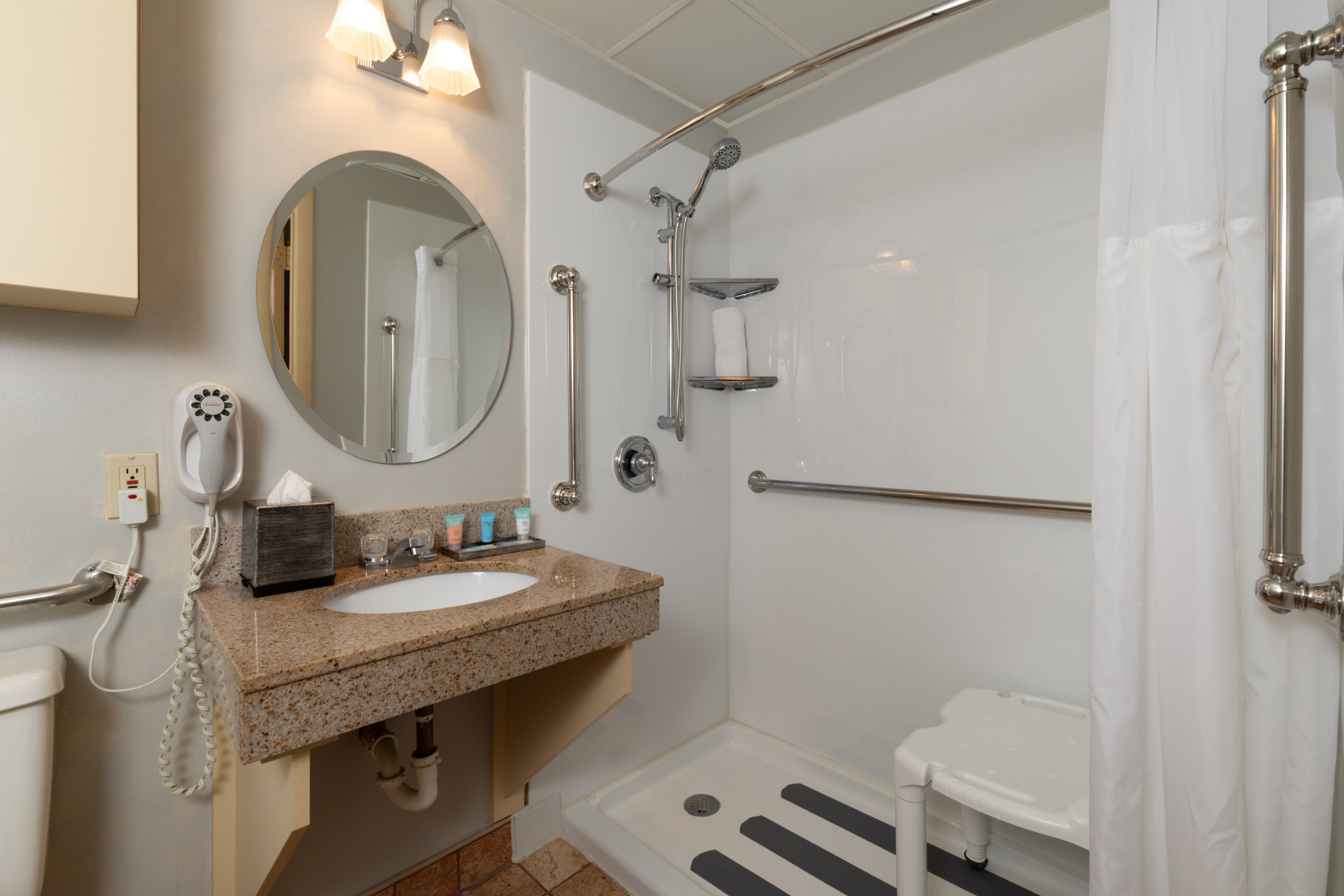 Un baño con lavamanos, espejo, ducha e inodoro.