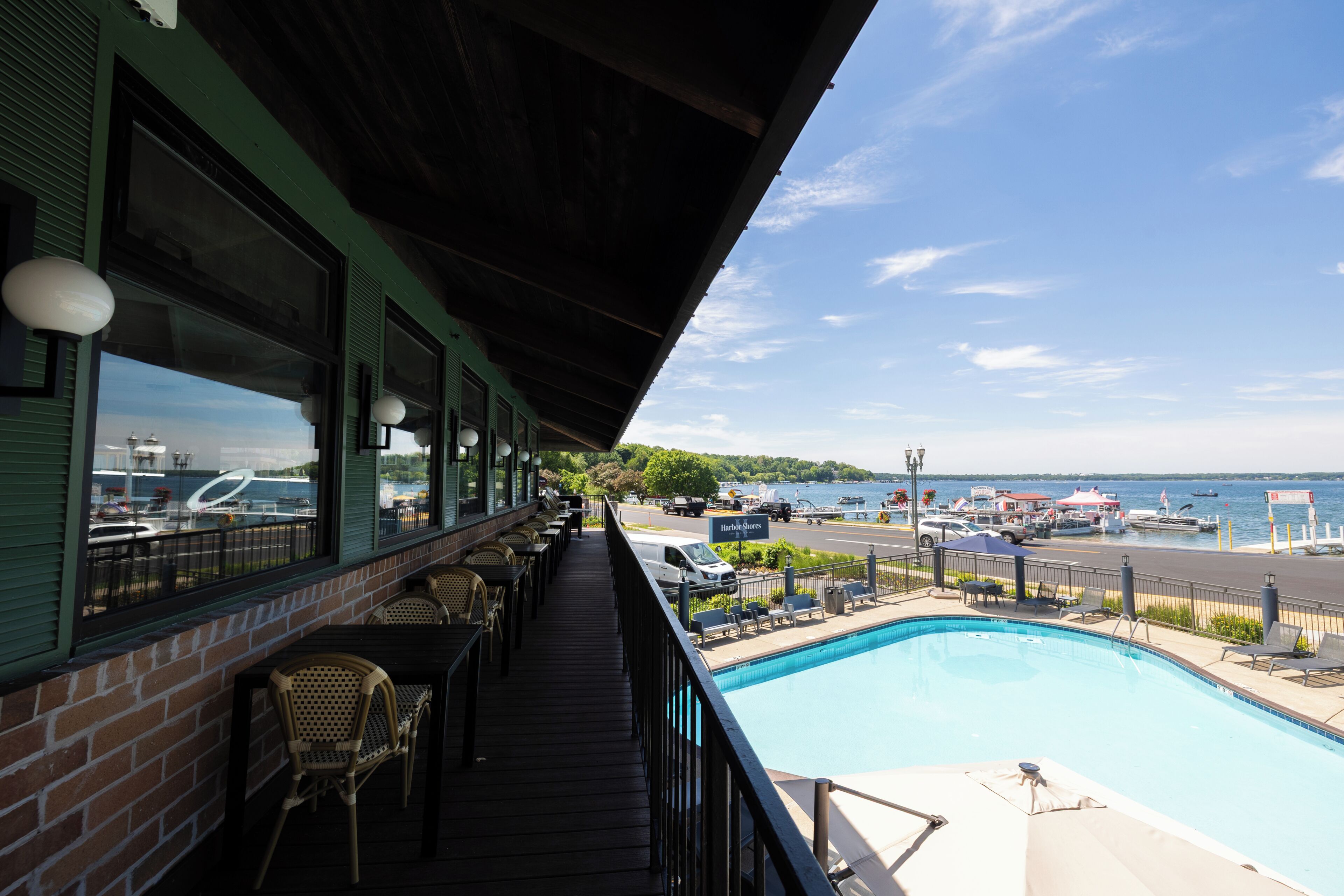 A poolside area with a view of the water, outdoor seating, and a covered deck.