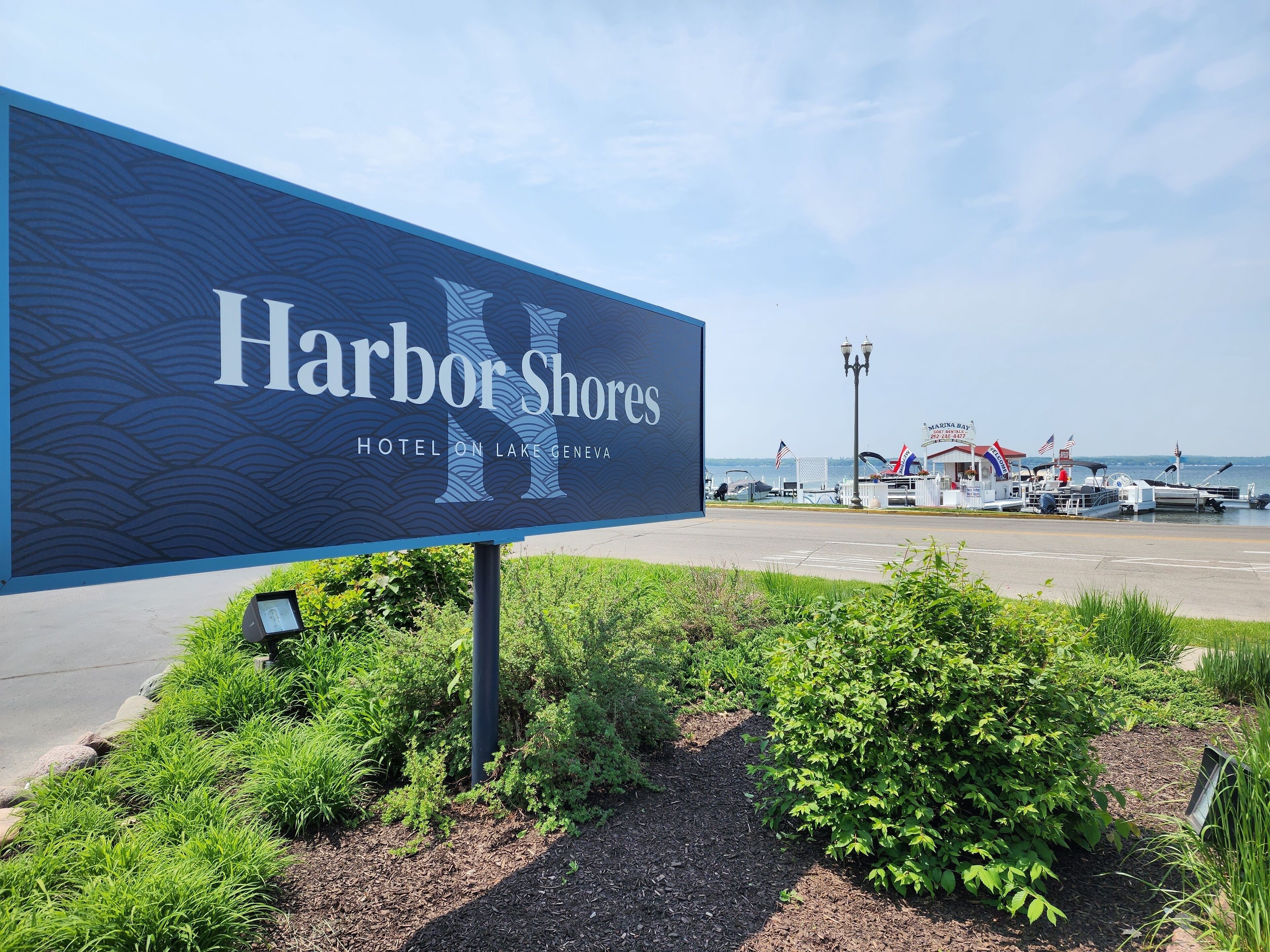 Señal del Hotel Harbor Shores en el lago Ginebra, con barcos amarrados al fondo.