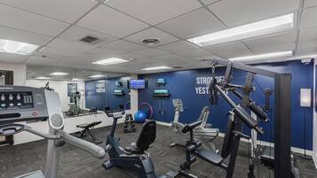 Un gimnasio con equipamiento de ejercicio, una pantalla digital y mensajes motivacionales en la pared.