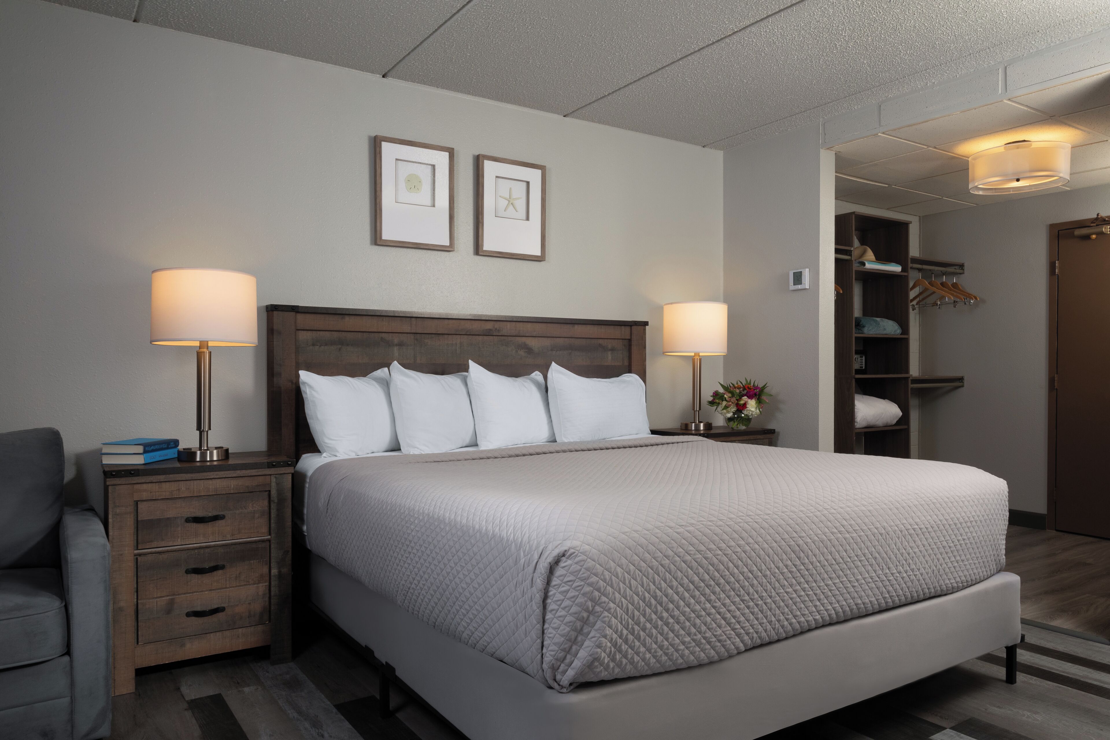 A neatly arranged hotel room with a large bed, two bedside tables with lamps, a chair, and a wardrobe.