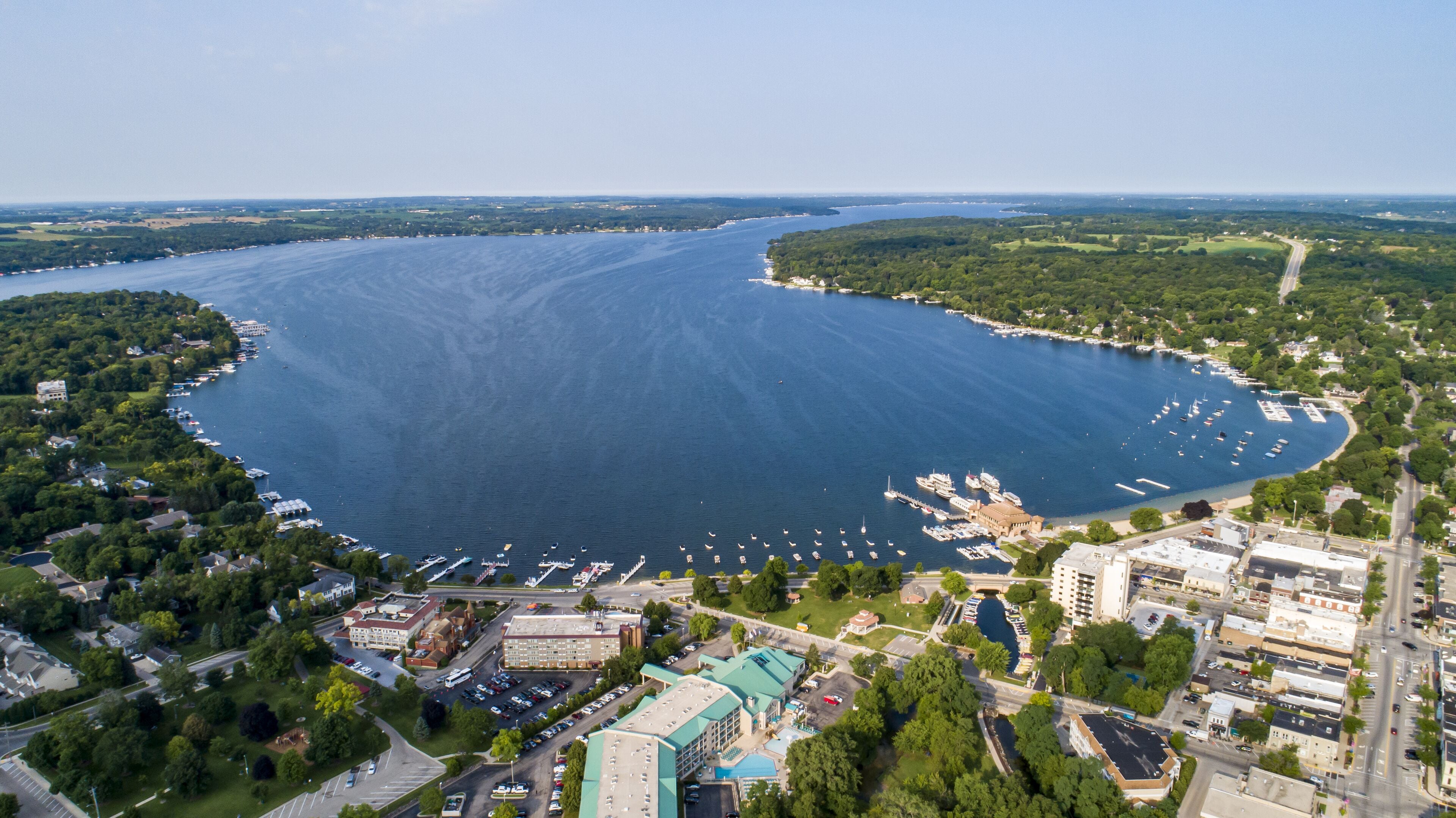 An aerial view of a coastal town with a marina, buildings, and roads.
