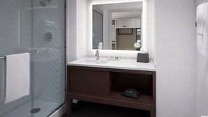 Une salle de bain moderne avec une douche à parois de verre, un lavabo blanc et un grand miroir.