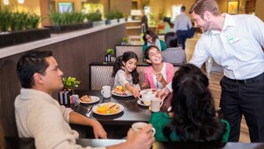Un grupo de personas cenando en el restaurante de un hotel, atendidas por un camarero.