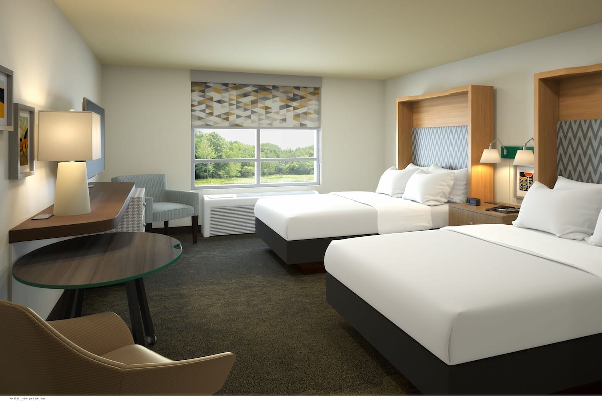 A hotel room with two beds, a desk with a lamp, a chair, and a view of the outdoors.
