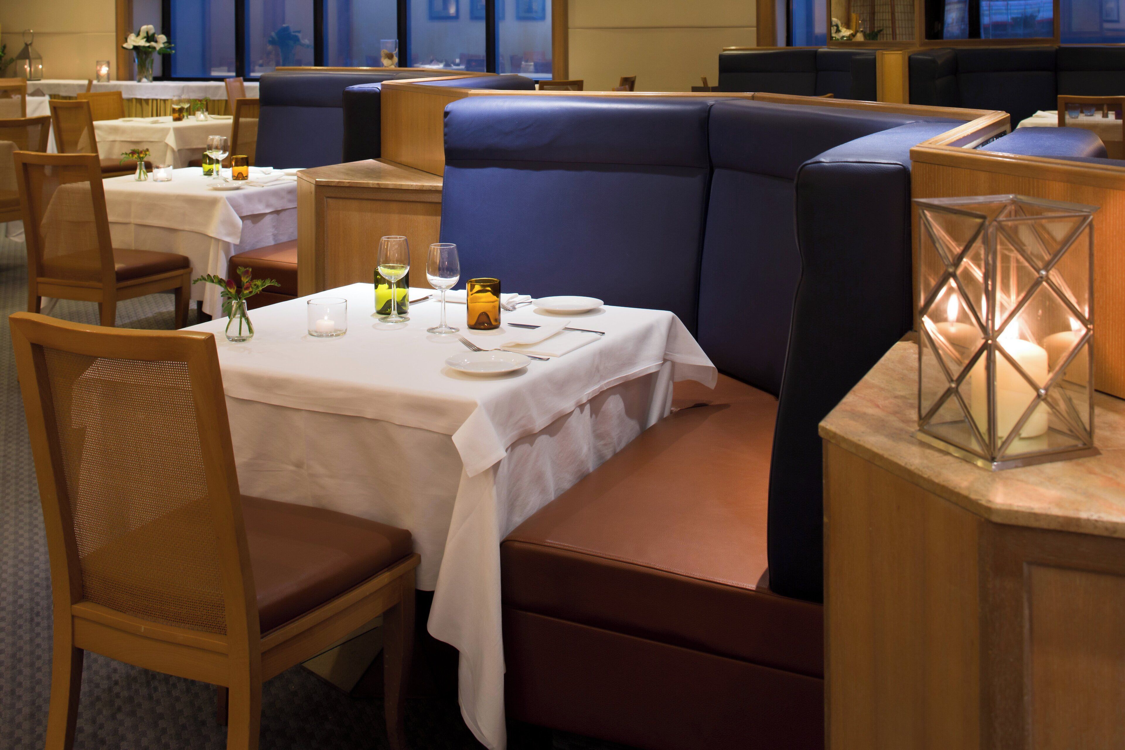 A restaurant with booths and tables, some with candles and flowers.