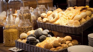 A buffet with various breads and pastries displayed in wicker baskets.