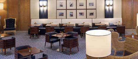 A hotel lobby with a seating area, tables, and a patterned floor.