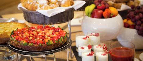 A buffet with various food items including pastries, fruits, and desserts.
