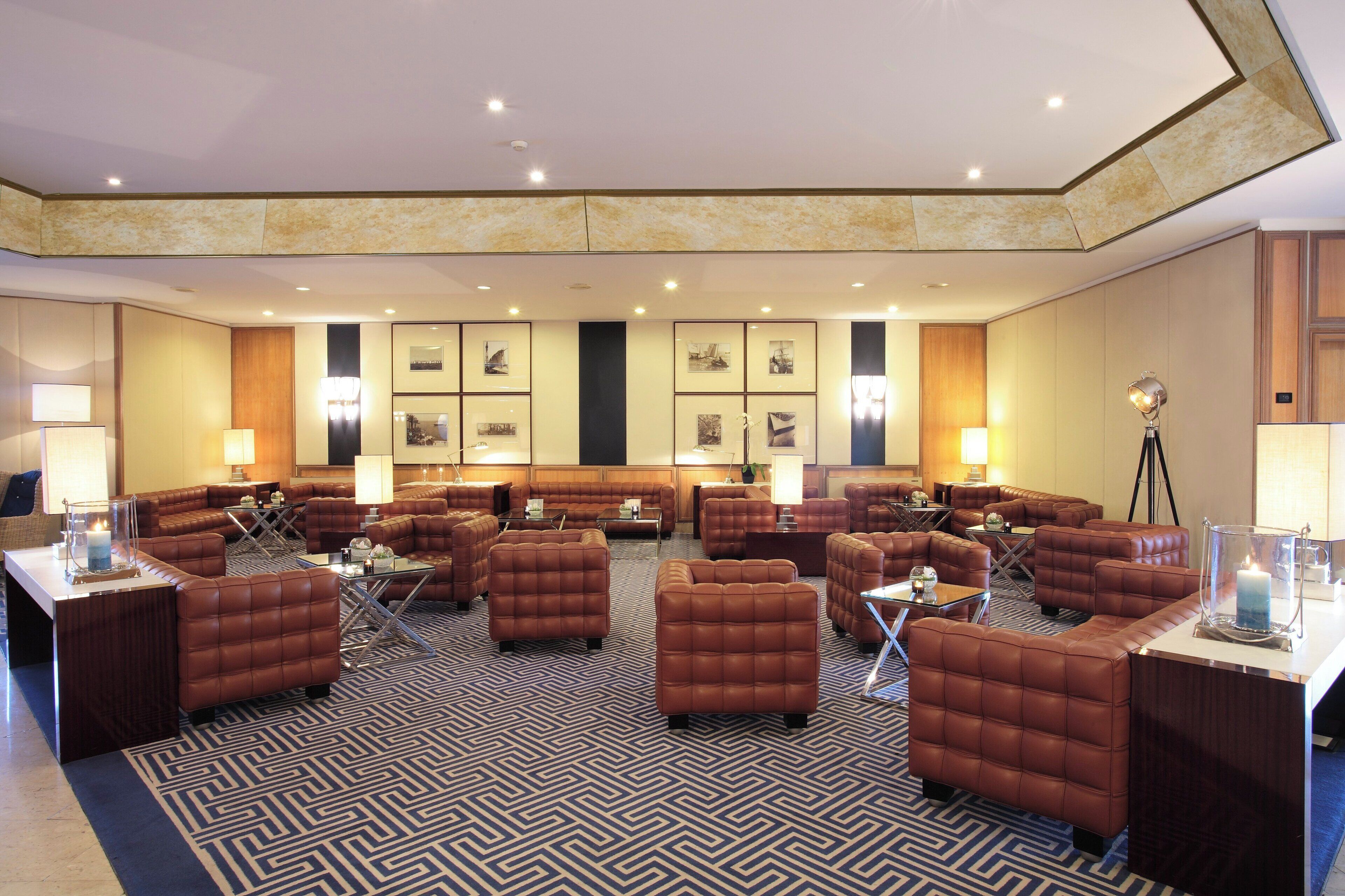 A spacious lobby with multiple seating areas, including sofas and armchairs, arranged around a central coffee table.