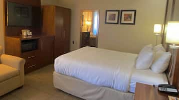 A hotel room with a bed, a desk with a phone, a TV, and a wardrobe.