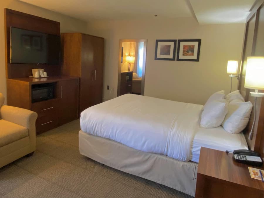 A hotel room with a bed, a desk with a phone, a TV, and a wardrobe.