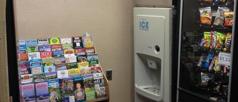 A vending machine with snacks, an ice dispenser, and a display of travel brochures.