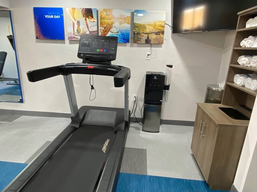 A gym with a treadmill, a water dispenser, and exercise equipment.