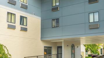 A multi-story building with a flat roof and a covered entrance area.