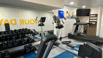 A gym with exercise equipment, a treadmill, and a wall with motivational text.