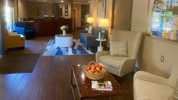 A hotel lobby with a reception desk, seating area, and a coffee table with a fruit basket.