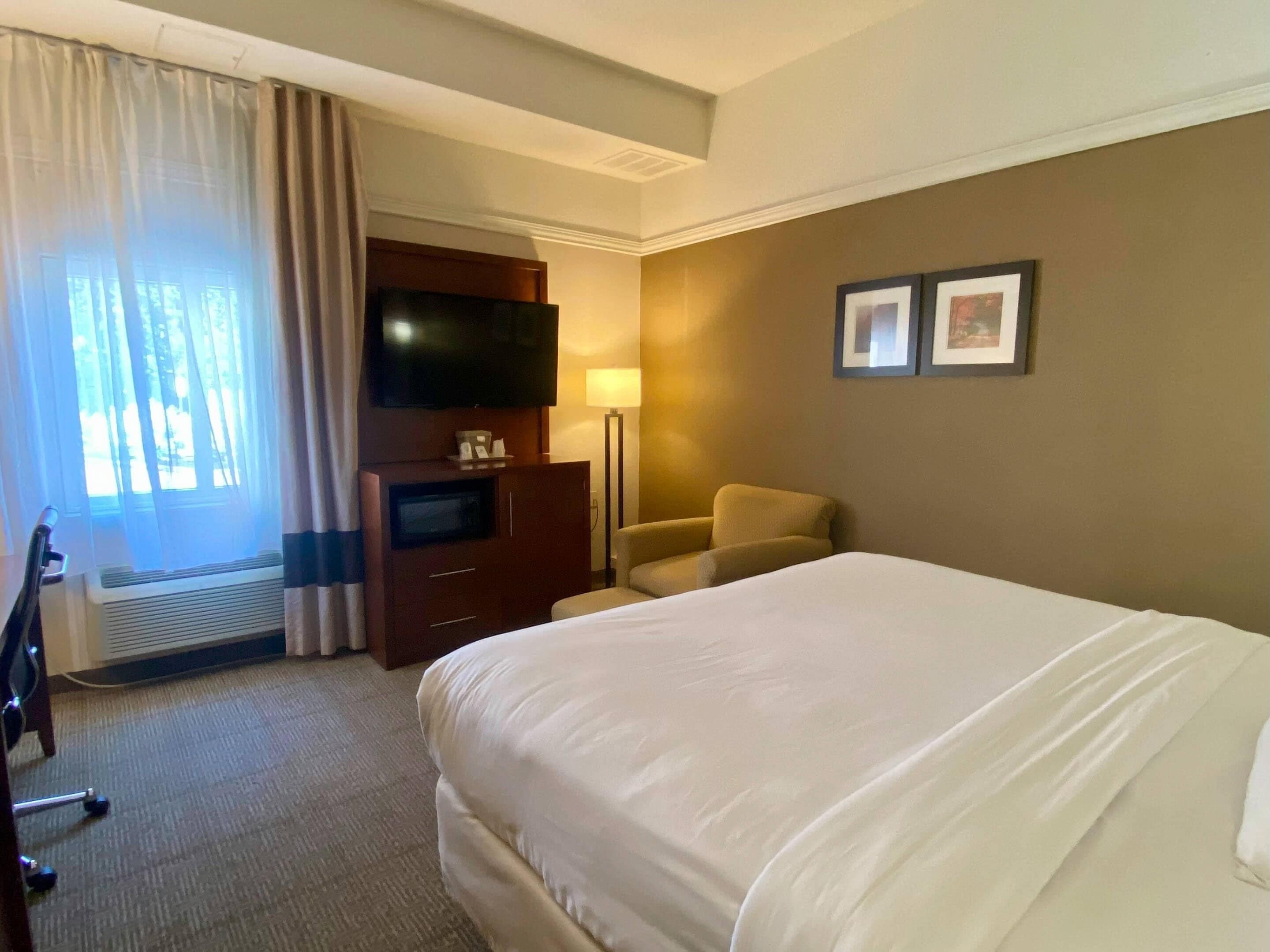 Een hotelkamer met een groot bed, een televisie, een bureau en een stoel.