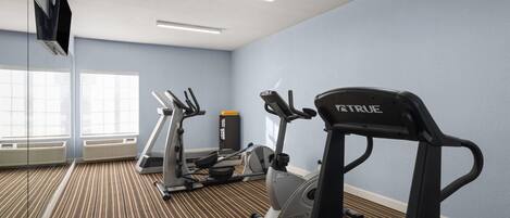 A gym with treadmills, a stationary bike, and a rowing machine.