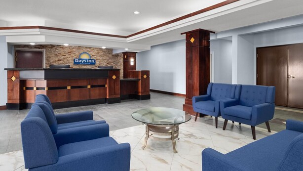 A hotel lobby with a reception desk, blue sofas, and a glass coffee table.