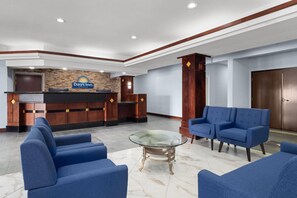 A hotel lobby with a reception desk, blue sofas, and a glass coffee table. - Days Inn by Wyndham Dodge City (Dodge City)