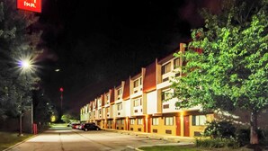 Un hotel Red Roof Inn amb una filera d'edificis de disseny uniforme, un aparcament i il·luminació de carrer.