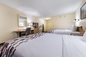 Une chambre d’hôtel avec deux lits, un bureau, une chaise, une télévision et un miroir.