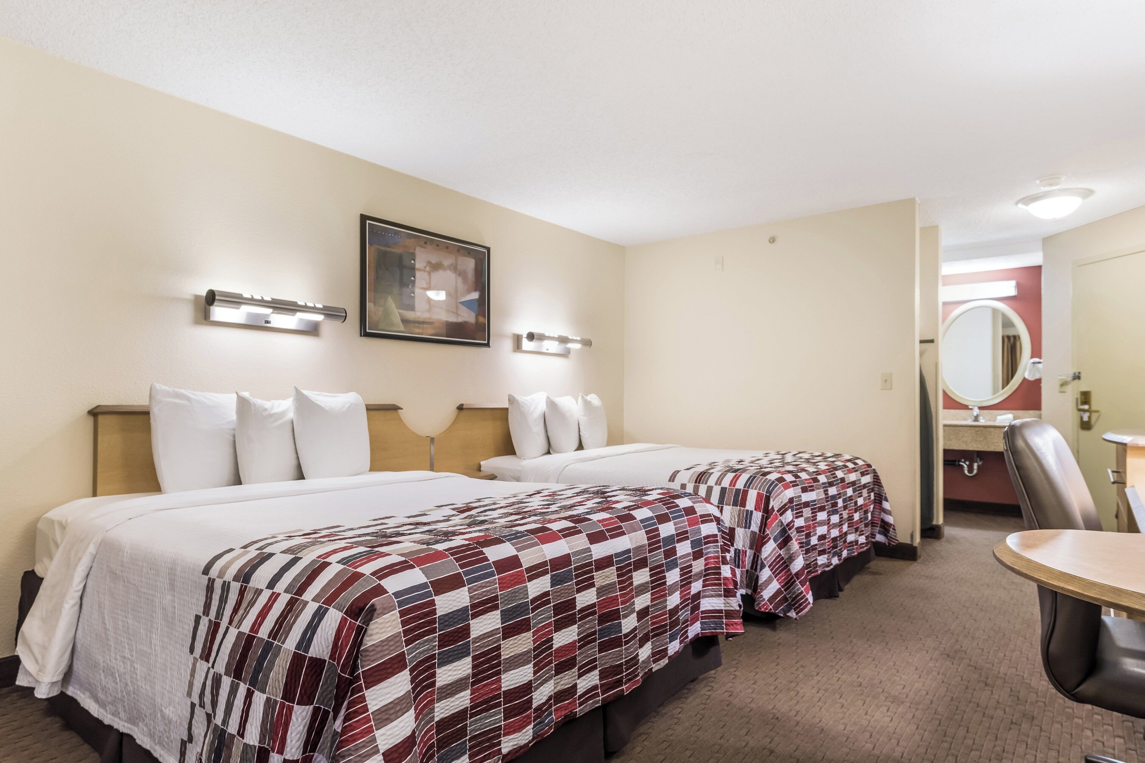 Une chambre d’hôtel avec deux lits, un coin salon et une salle de bain.