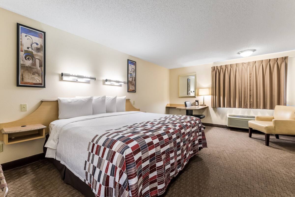 Een hotelkamer met een groot bed, een bureau, een stoel en een badkamer.