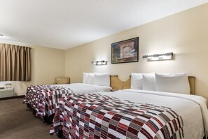 Una habitación de hotel con dos camas, un ventanal con cortinas, un cuadro en la pared y una mesita de noche con lámpara.