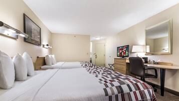 Ein Hotelzimmer mit zwei Betten, einem Schreibtisch, einem Stuhl, einem Fernseher und einem Bild an der Wand.