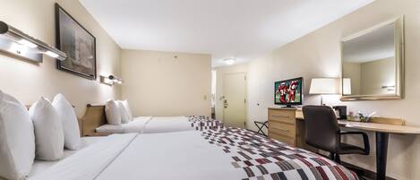 A hotel room with two beds, a desk, a chair, a television, and a painting on the wall.