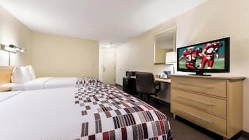 A hotel room with two beds, a desk, a chair, a television, and a minibar.