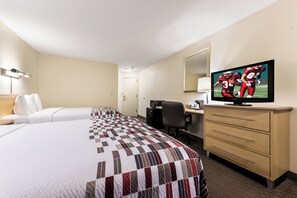 Een hotelkamer met twee bedden, een bureau, een stoel, een televisie en een minibar.
