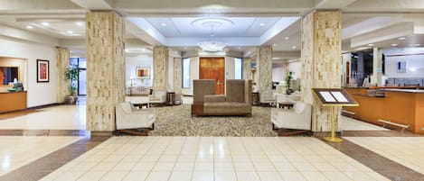 A spacious lobby with a reception desk, seating area, and a patterned floor.